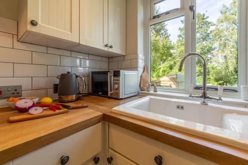eine Küche mit einer Spüle und einer Mikrowelle in der Unterkunft Willow Cottage in North Creake
