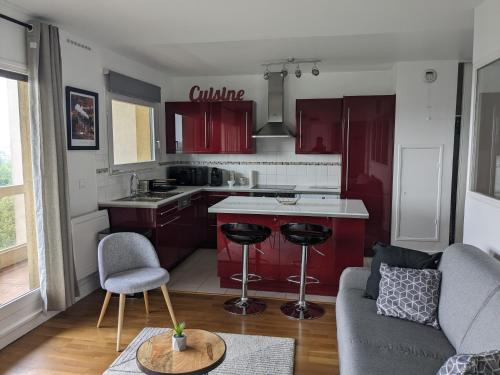 un salon avec un canapé et une cuisine avec des armoires rouges dans l'établissement PUTEAUX- La défense Arena Appartement vue tour Eiffel, à Puteaux