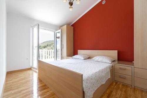 ein Schlafzimmer mit einem Bett mit einer orangefarbenen Wand in der Unterkunft Holiday house with a swimming pool Prizba, Korcula - 199 in Prizba