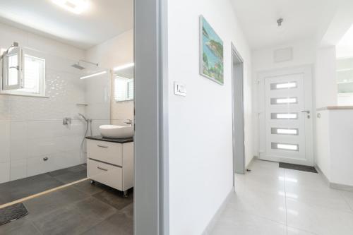 ein weißes Badezimmer mit Waschbecken und Spiegel in der Unterkunft Holiday house with a swimming pool Prizba, Korcula - 199 in Prizba