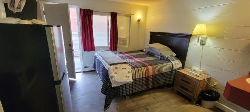 a small bedroom with a bed and a window at Southview Motel in Westlock