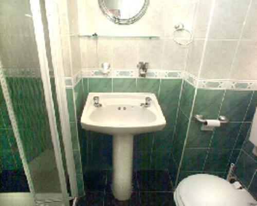 a bathroom with a sink and a toilet and a mirror at Piccolino Hyde Park Hotel in London