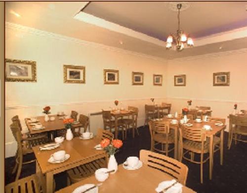 une salle à manger avec des tables et des chaises en bois dans l'établissement Piccolino Hyde Park Hotel, à Londres