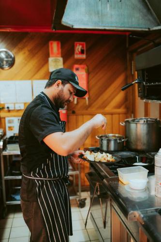 a man in a kitchen preparing food on a stove at Tall Timbers Tasmania in Smithton