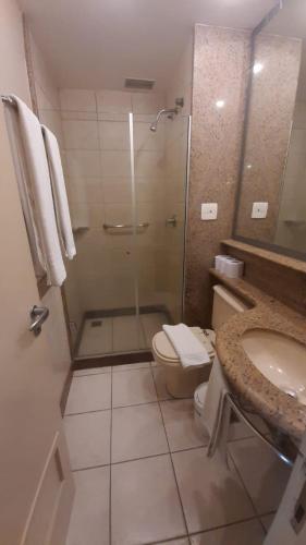 a bathroom with a shower and a toilet and a sink at Flat Barra da Tijuca - Gastão Sengés in Rio de Janeiro