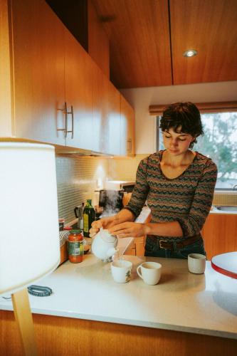 a woman standing in a kitchen preparing food at Tall Timbers Tasmania in Smithton