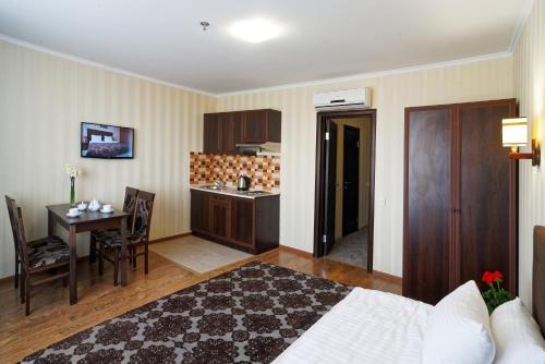 a bedroom with a bed and a table and a kitchen at Lisova Pisnia Resort Hotel in Truskavets