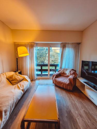 1 dormitorio con cama, sofá y ventana en Departamento Plaza en San Martín de los Andes