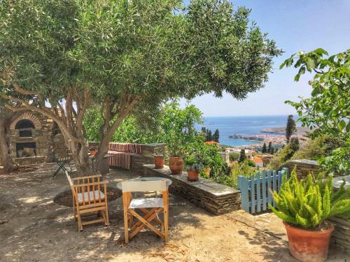 una mesa y sillas sentadas bajo un árbol en The Walnut Tree - Cycladic Getaway with Sea Views, en Lámira