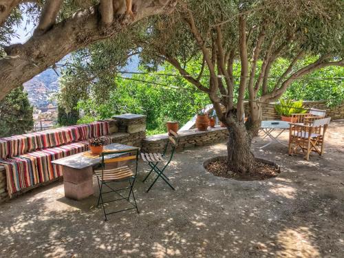 a patio with a table and chairs under a tree at The Walnut Tree - Cycladic Getaway with Sea Views in Lámira