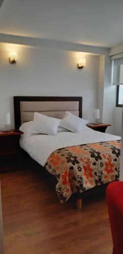a bedroom with a bed with a floral blanket on it at 100 Wonderful House in Bogotá