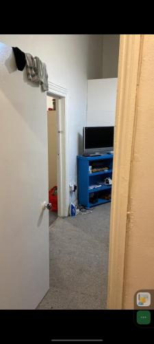 Zimmer mit einer Tür, die zu einem Zimmer mit einem TV führt in der Unterkunft 2 single bed in one room in a shared apartment in Bradford