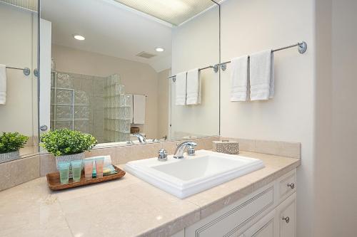 La salle de bains est pourvue d'un lavabo blanc et d'un miroir. dans l'établissement Kuu Lei Villa, à Princeville