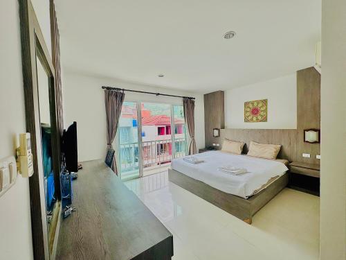 a bedroom with a large bed and a balcony at Cocoon Patong Hotel in Patong Beach