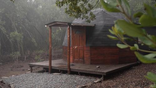 a small wooden cabin with a deck in the woods at Lircaydomohostal - Domo 40m2 para 4 personas in Talca