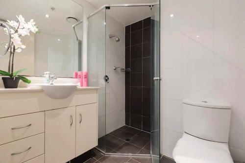 a bathroom with a shower and a toilet and a sink at Cozy Chic Haven: Modern Comfort in Gold Coast