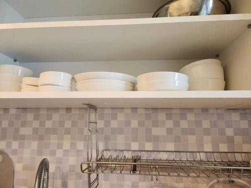 a shelf with white dishes on it in a kitchen at 10 mins from Nowon Station! Happy House in Seoul