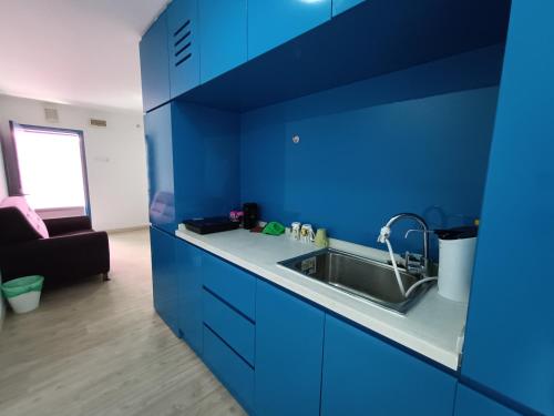 cocina azul con fregadero y sofá en Halo Sunday Empire City by Kenangan Home 4 Paxs Room en Petaling Jaya