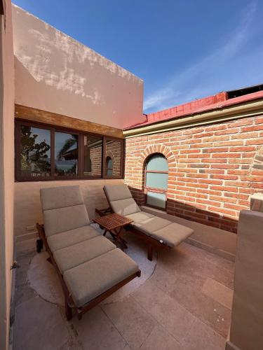 a patio with chairs and a table and a brick wall at Hotel Lindo Ajijic Bed & Breakfast in Ajijic