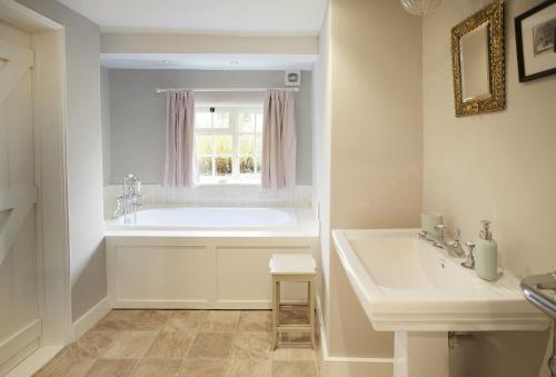 uma casa de banho com uma banheira, um lavatório e uma janela em Coral Cottage em Coneysthorpe
