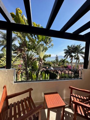 a balcony with two wooden chairs and palm trees at Hotel Lindo Ajijic Bed & Breakfast in Ajijic
