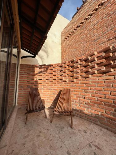two wooden chairs sitting next to a brick wall at Hotel Lindo Ajijic Bed & Breakfast in Ajijic