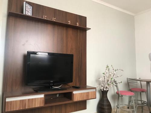 a flat screen tv sitting on a wooden entertainment center at Apartamento mobiliado Piracicaba in Piracicaba