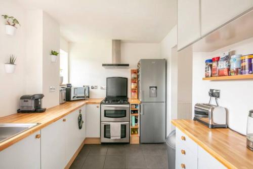 uma cozinha com armários brancos e um frigorífico de aço inoxidável em Double Room, Large TV, With Great Transport Links em Bolton