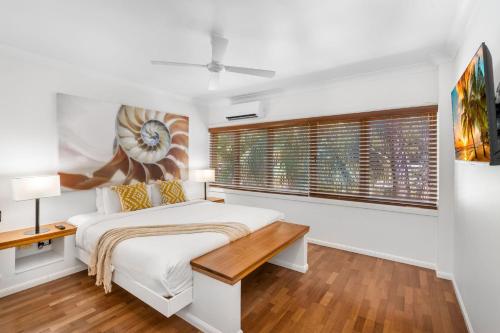 ein weißes Schlafzimmer mit einem Bett und einem Fenster in der Unterkunft Belle Escapes Poolview Suite 77 Alamanda Resort Palm Cove in Palm Cove