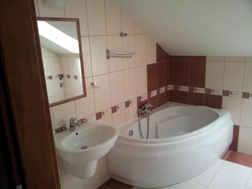 a bathroom with a tub and a sink and a mirror at Belweder Apartamenty i Pokoje in Wisła