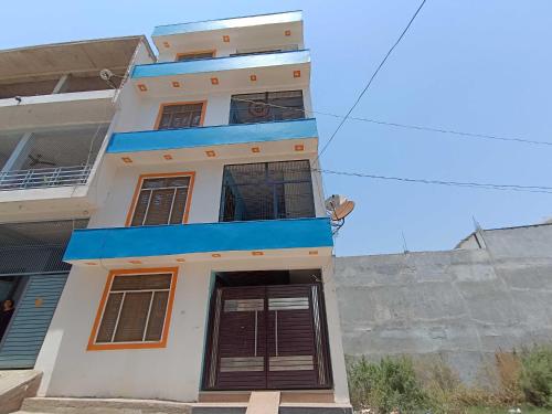 a tall white building with a blue balcony at OYO HOME Satvik Homestay in Ayodhya