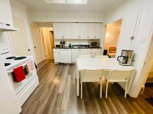 a kitchen with a white table and white cabinets at Artistic Apartment Near Downtown in Victoria
