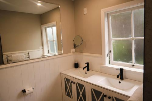 a bathroom with two sinks and a large mirror at Victorian Designs - Spacious Home in Rotorua Central in Rotorua