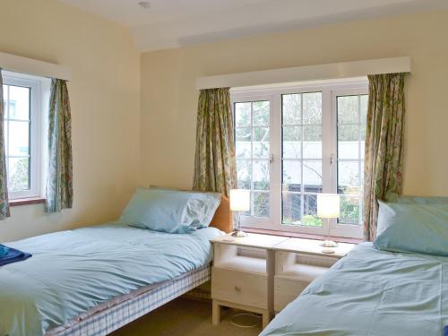 two beds in a room with two windows at Green Hedges in Budleigh Salterton
