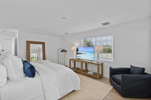 a white bedroom with a bed and a chair at Santa Lucia Estate - Hotel Homes in West Palm Beach