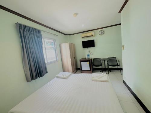 a room with a bed and a table and a television at Cocoon Omaya Guest House in Patong Beach