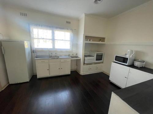 an empty kitchen with white cabinets and a window at Sandown Springvale close to shop/station in Springvale