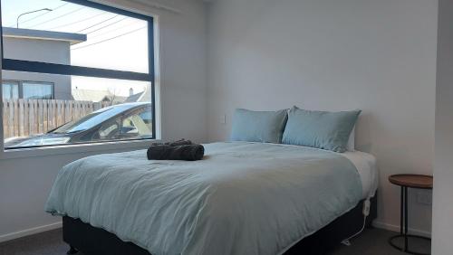 sypialnia z dużym łóżkiem i oknem w obiekcie Sleek Suite by the Sand (2 bedroom) w mieście Dunedin