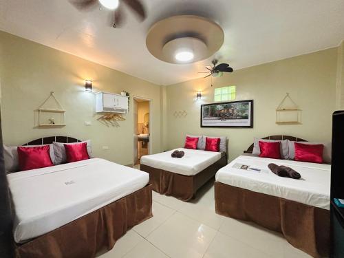 twee bedden in een kamer met rode kussens erop bij Panari Lodge El Nido in El Nido
