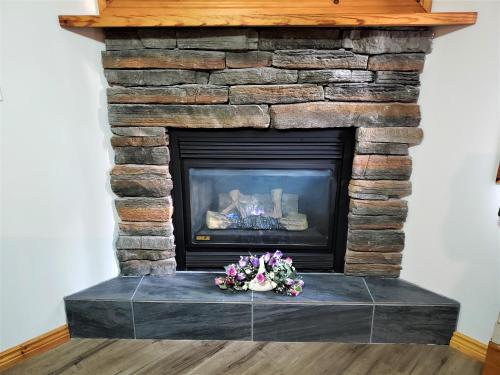 a stone fireplace with flowers on a table at Knights Inn Colonial Fireside Inn in Pembroke