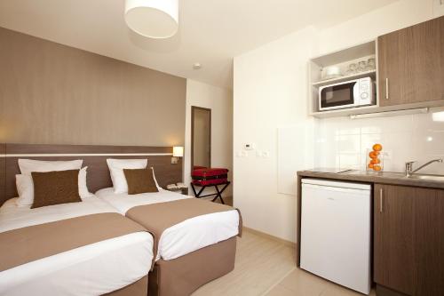 ein Hotelzimmer mit einem großen Bett und einer Küche in der Unterkunft Séjours & Affaires Massy Atlantis in Massy