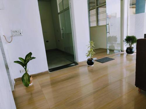 an empty room with potted plants on a wooden floor at OYO RU Hotel And Banquet Hall in Rewāri