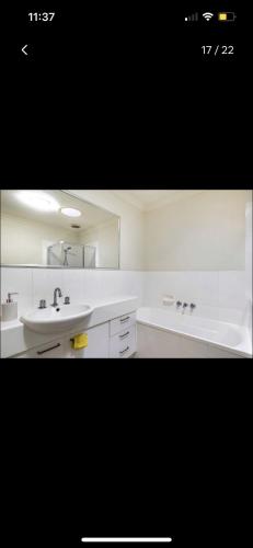 a white bathroom with a sink and a tub at Private Room in Shared Accommodation in Redcliffe