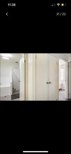 a room with white cabinets and a mirror at Private Room in Shared Accommodation in Redcliffe