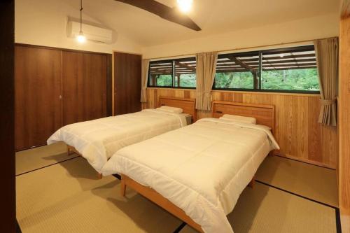 2 camas en una habitación con ventana en 【コテージくぎの】大谷川沿いの露天風呂があるコテージ, en Minami Aso