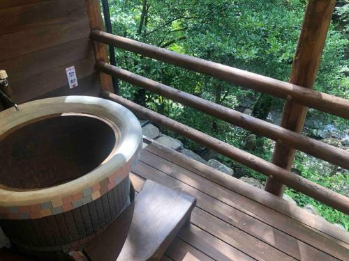 a bath tub on a wooden deck with a window at 【コテージくぎの】大谷川沿いの露天風呂があるコテージ in Minami Aso