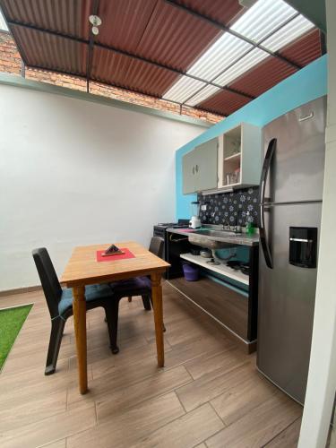 a kitchen with a wooden table and a refrigerator at Havana Dance School & Hostel in Cali