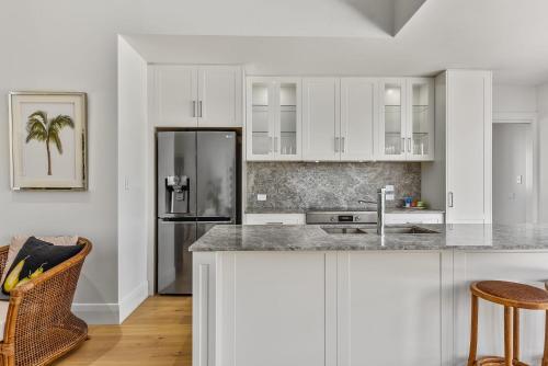 a kitchen with white cabinets and a stainless steel refrigerator at Robe Beach Stays in Robe