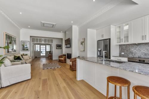 a kitchen and living room with white cabinets and a counter at Robe Beach Stays in Robe
