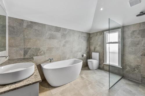 a bathroom with a large white tub and a toilet at Robe Beach Stays in Robe